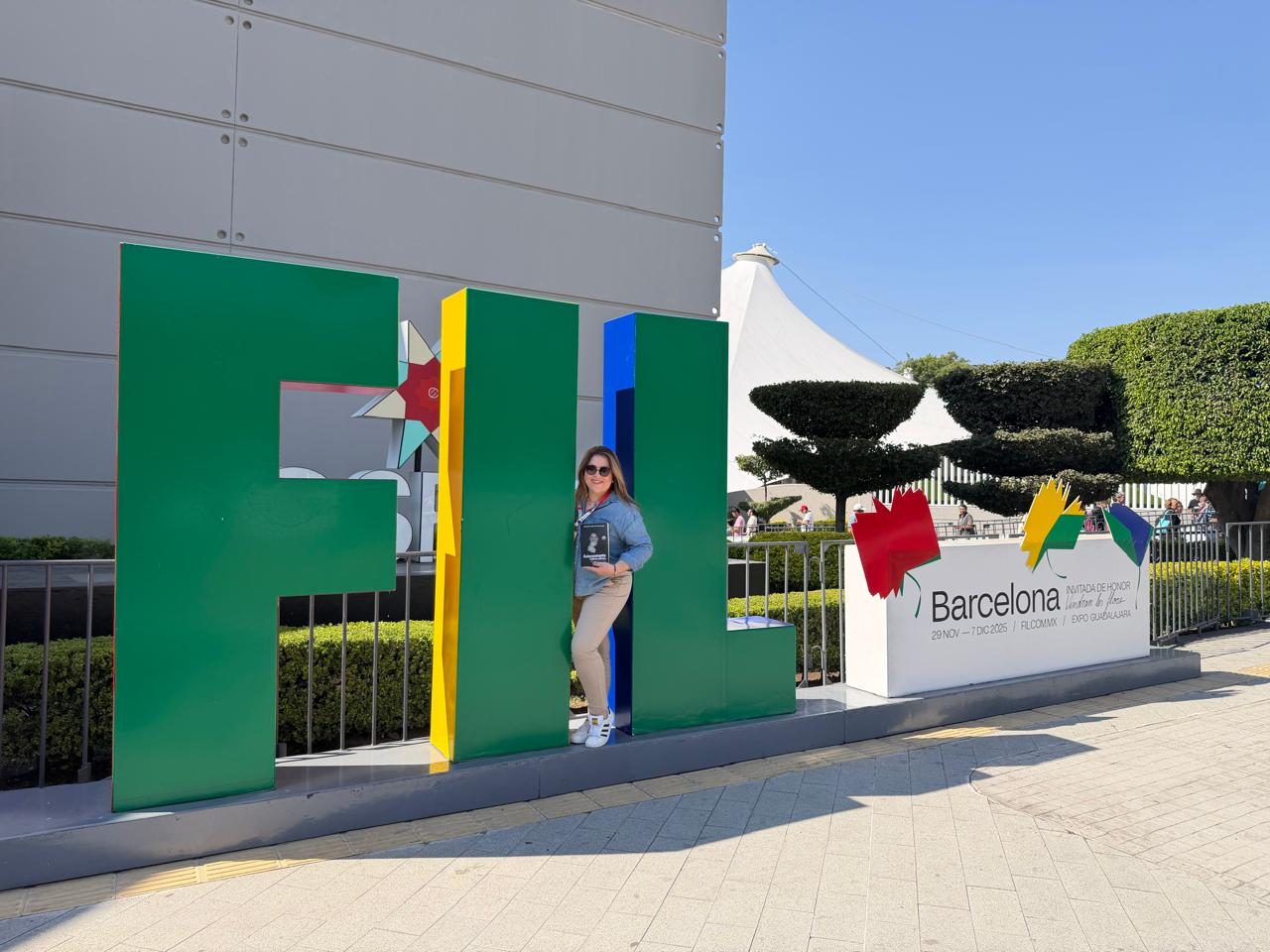 Jennifer Sierra Buitrago con su libro frente a las letras FIL en Expo Guadalajara